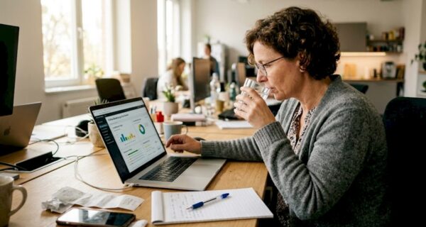 Ein Manager sitzt an seinem Schreibtisch im Büro und wirft einen Blick auf die aktuellen Online-Bewertungen.